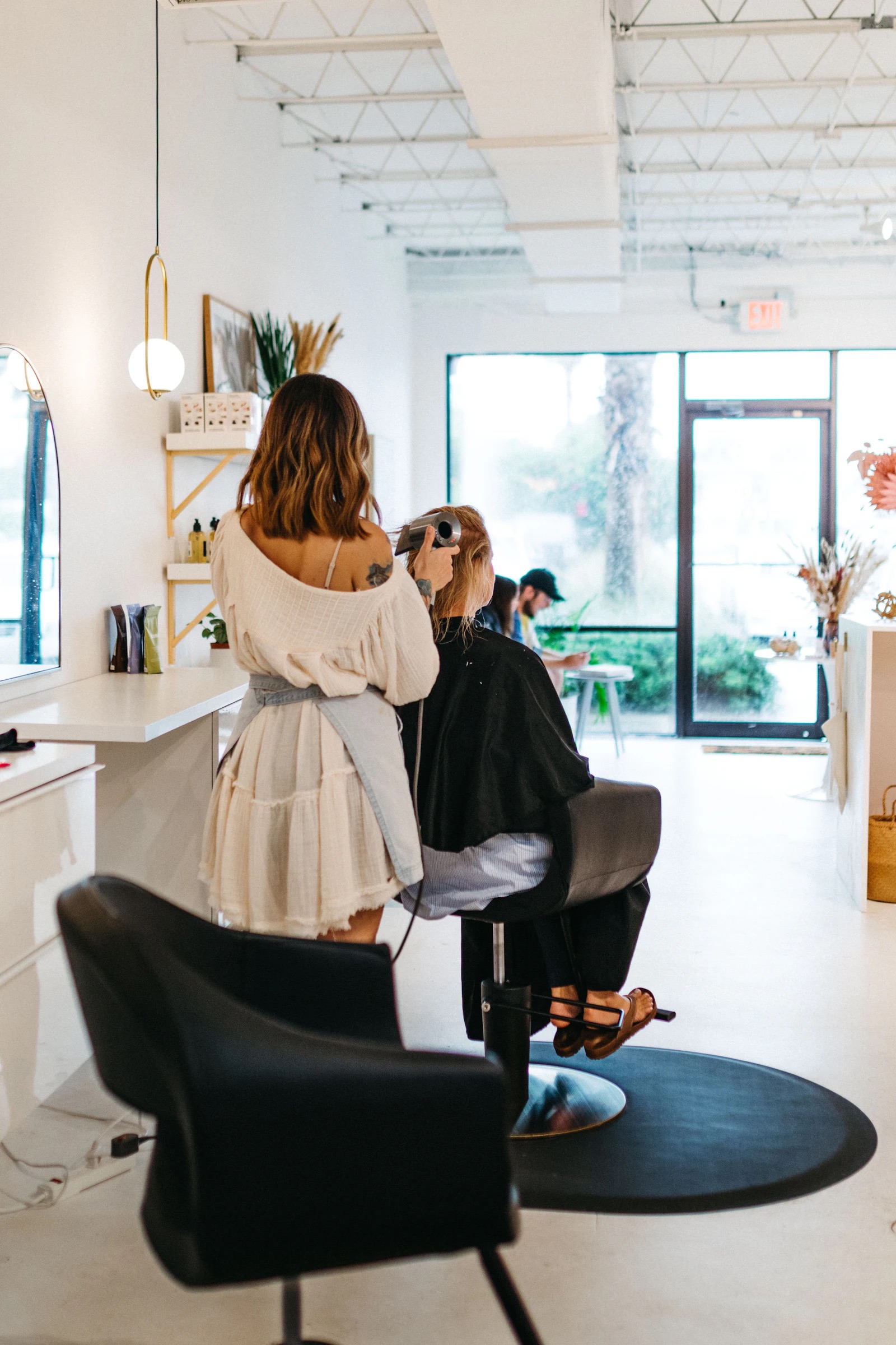 A client having her hair done in a bright, plant-filled salon